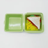 Porta merenda verde chiuso visto aperto con dentro un sandwich e patatine fritte