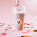 Bicchiere di plastica con cupola e cannucce pieno di frappe e etichetta tonda con cuore