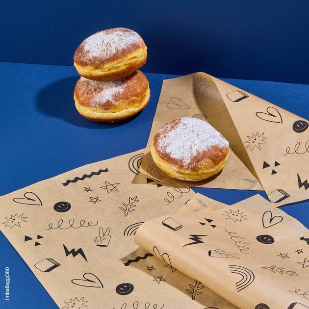 Carta antigrasso con fantasia smile, vicino a dei bomboloni su un tavolo azzurro