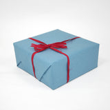 Pacco chiuso con carta azzurra e fiocco rosso