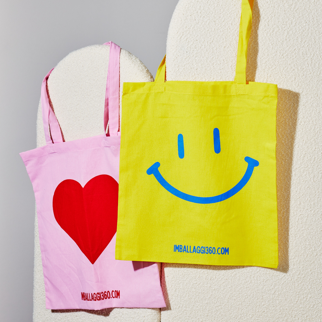 Shopper personalizzate appese, una gialla con smile ed una rosa con cuore rosso
