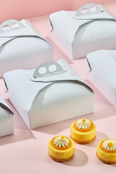 Scatole porta torte, chiuse bianche e tre pasticcini