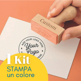 Timbro personalizzato con il tuo logo retto da una mano su un foglio timbrato. Scritta 1 kit stampa 1 colore