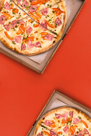 Cartone di pizza con dentro pizza su sfondo rosso