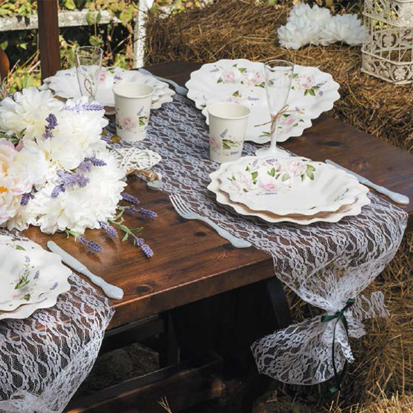 Tavola rustica apparecchiata con set monouso a fiori su bianco