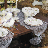 Tavola rustica apparecchiata con set monouso a fiori su bianco