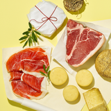 Tavola gialla con carta alimentare, prosciutto, salumi e formaggi 