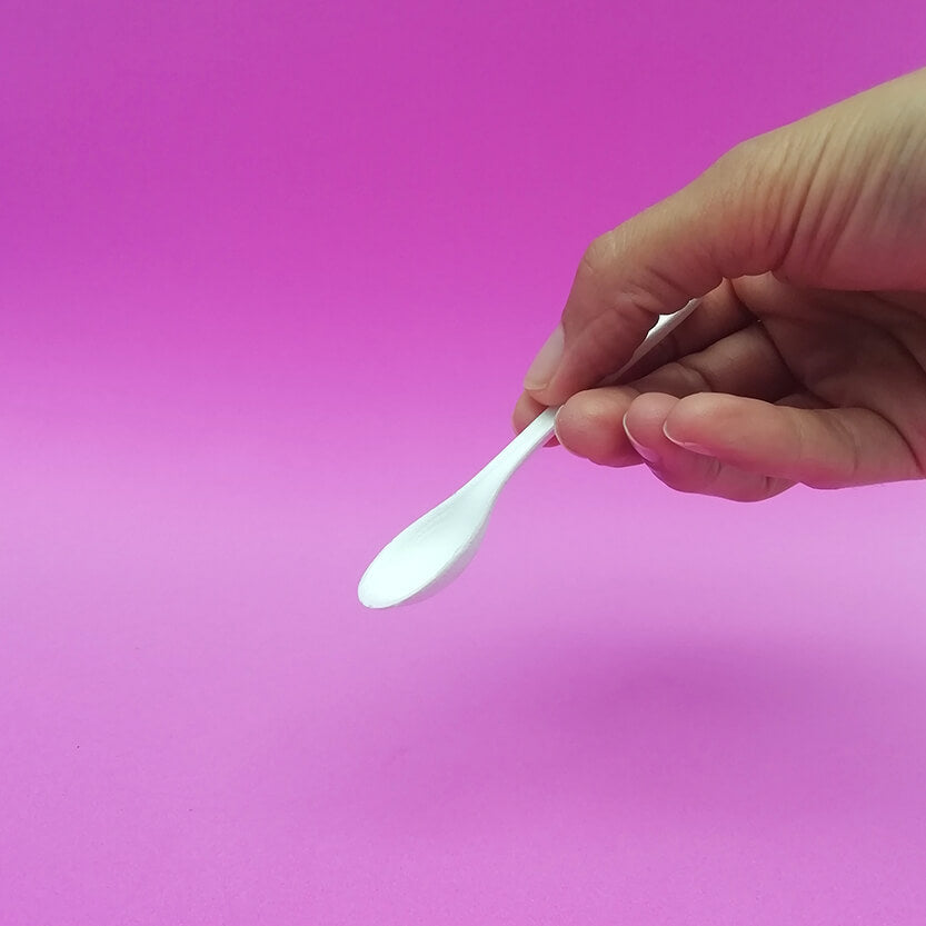 Mano che regge un cucchiaino di plastica 