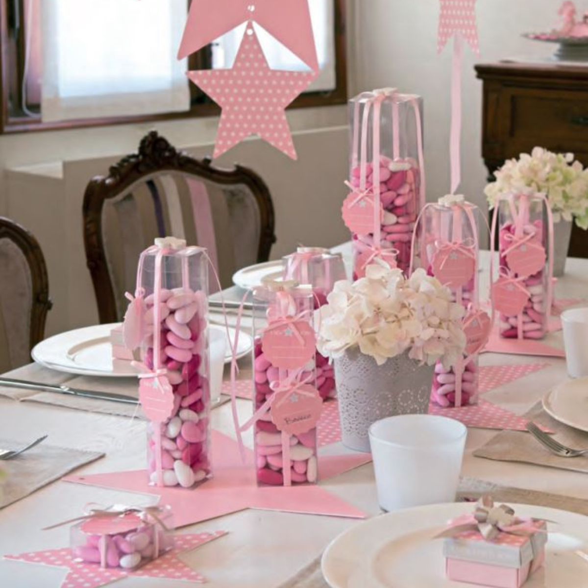 Tavola imbandita con  scatole trasparenti piene di confetti rosa