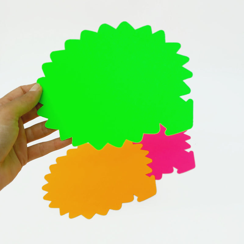 Cartellini segna prezzo, verde, fucsia e arancione fluo, retti da una mano