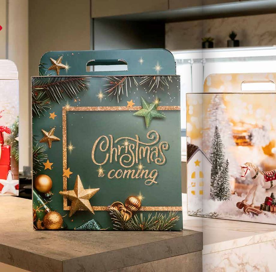 Scatola natalizia per panettone, color verde bottiglia con grafiche natalizie, su un tavolo assieme ad altre scatole di colore diverso 