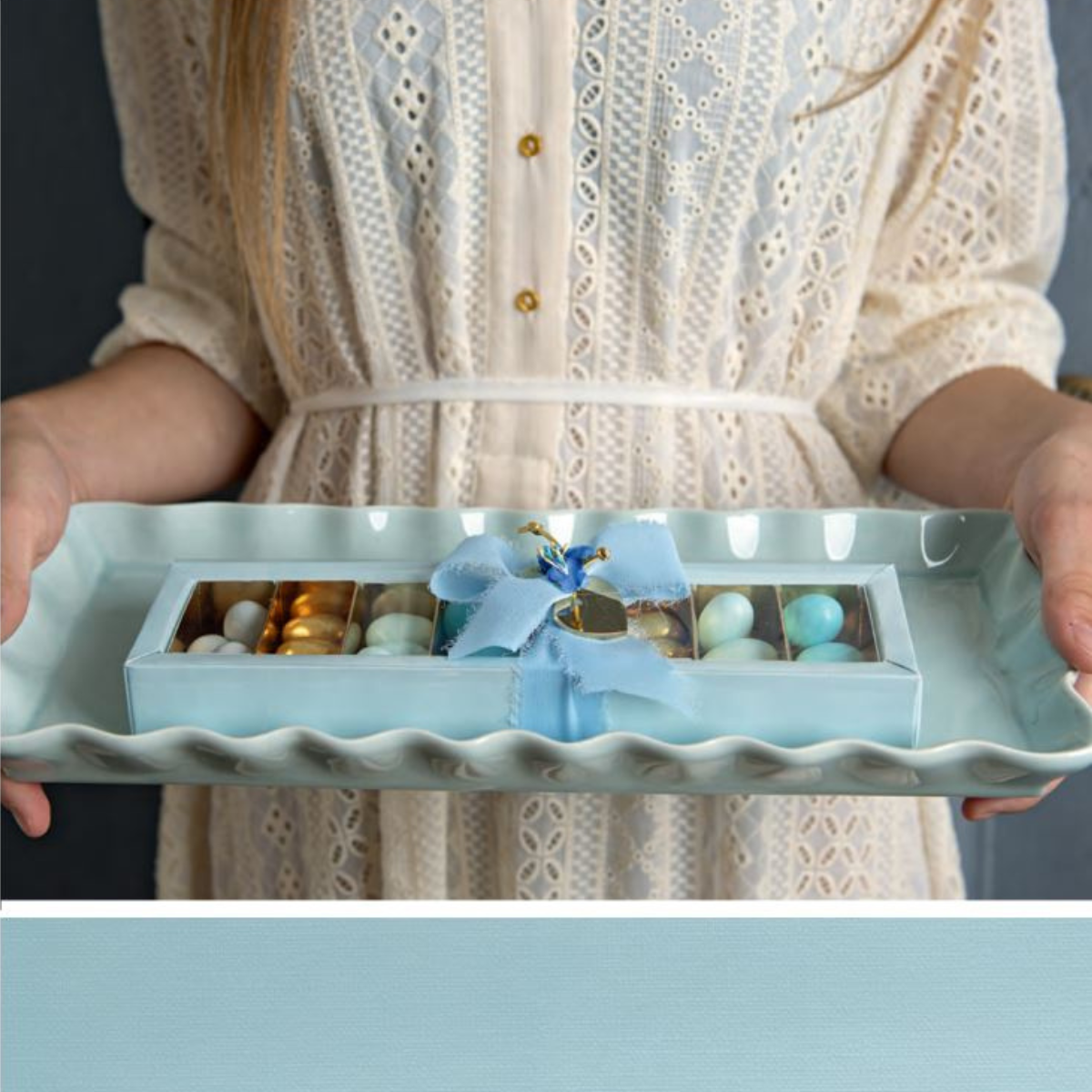 Ragazza che tiene in mano vassoio con confezione piena di confetti. tutto sui toni del blu