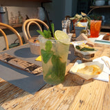 Bicchiere trasparente riutilizzabile ripieno di mojito su tavola apparecchiata per aperitivo 