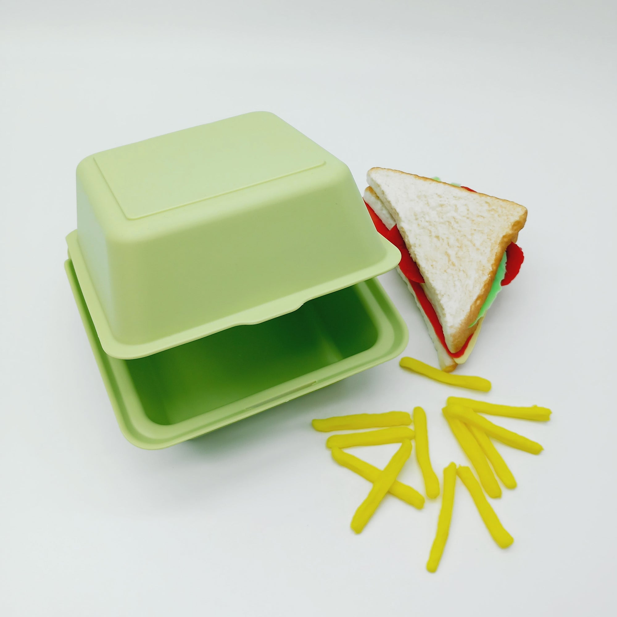 Porta merenda verde chiuso visto  aperto ocn accanto patatine fritte ed un sandwich