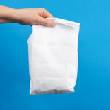 Sacchetto pane bianco tenuto da una mano su sfondo blu