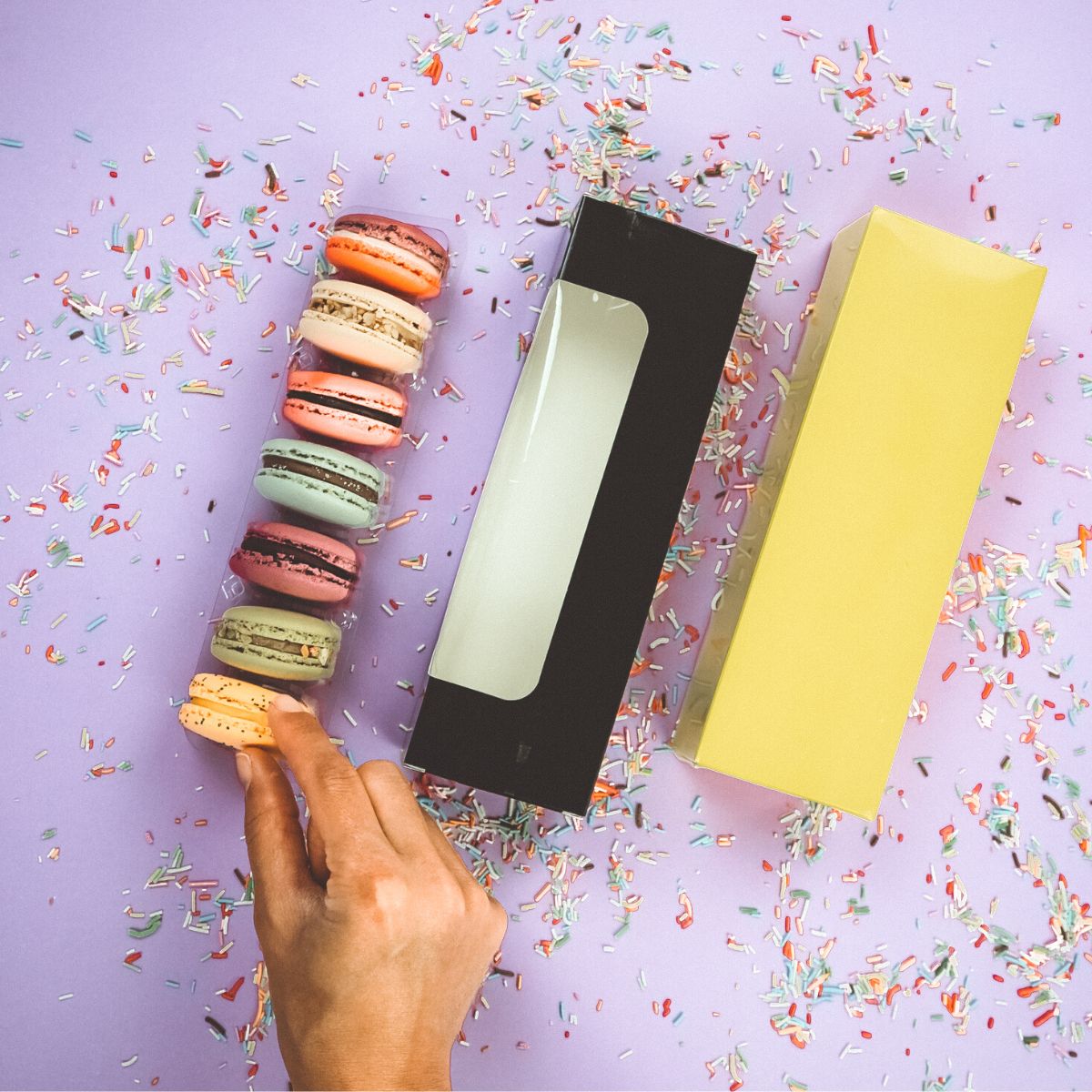 tre tipologie di scatole per macarons, una trasparente piena, una nera con finestra ed una gialla