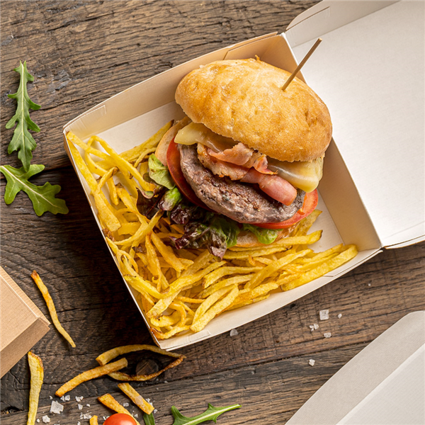 Scatola per hamburger, di carta, color avana, mostrata aperta con dentro un panino e delle patatine, su un tavolo di legno