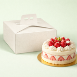 Torta da pasticceria vicino ad una scatola porta torte bianca 