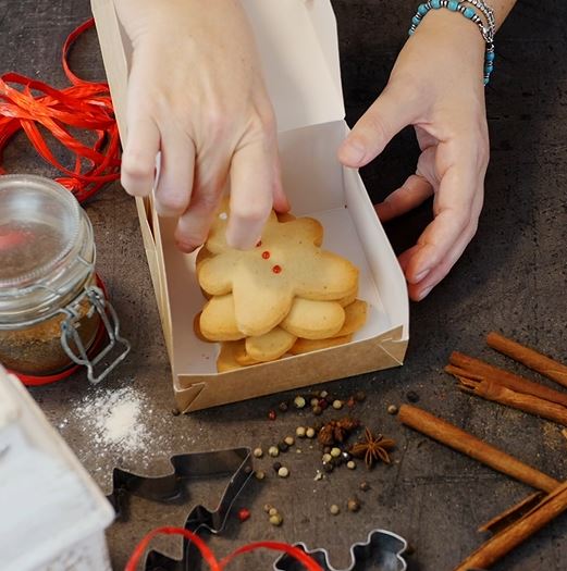 Scatola torta avana aperta con dentro biscotti e mani che li prendono 