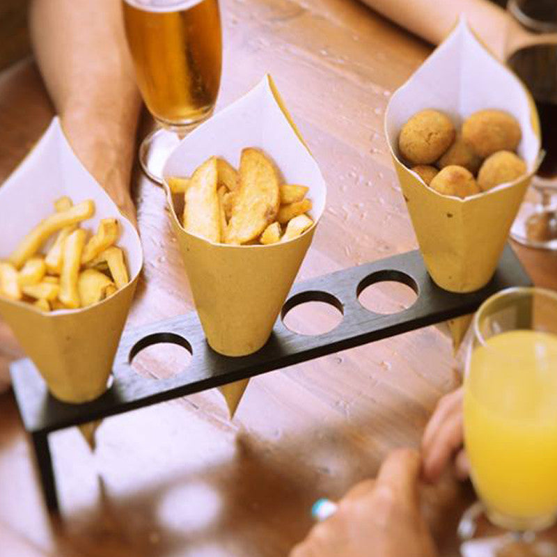 Tavola con sopra porta coni per fritto, con tre coni di carta pe fritti, pieni di patate