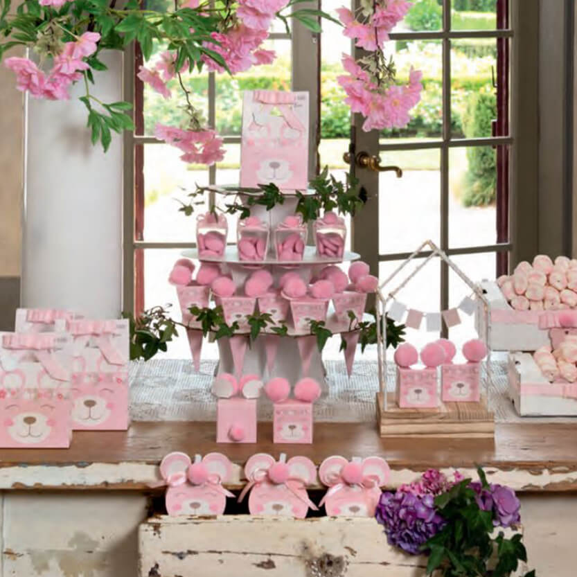 Tavola di legno con sopra tante bomboniere rosa