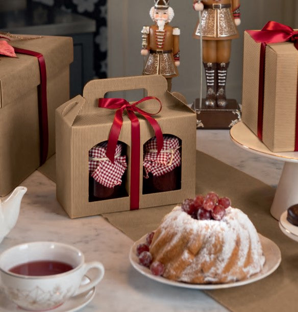 Tavola con scatole ondulate avana e confezioni regalo, una tazza di te e un dolce 