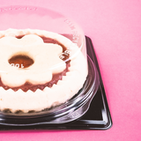 Dettaglio di vassoio nero con coperchio trasparente con dentro torta 