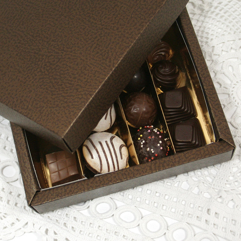 Dettaglio di scatola scura  con divisori dorati piena di cioccolatini, 