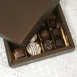 Dettaglio di scatola scura  con divisori dorati piena di cioccolatini, 