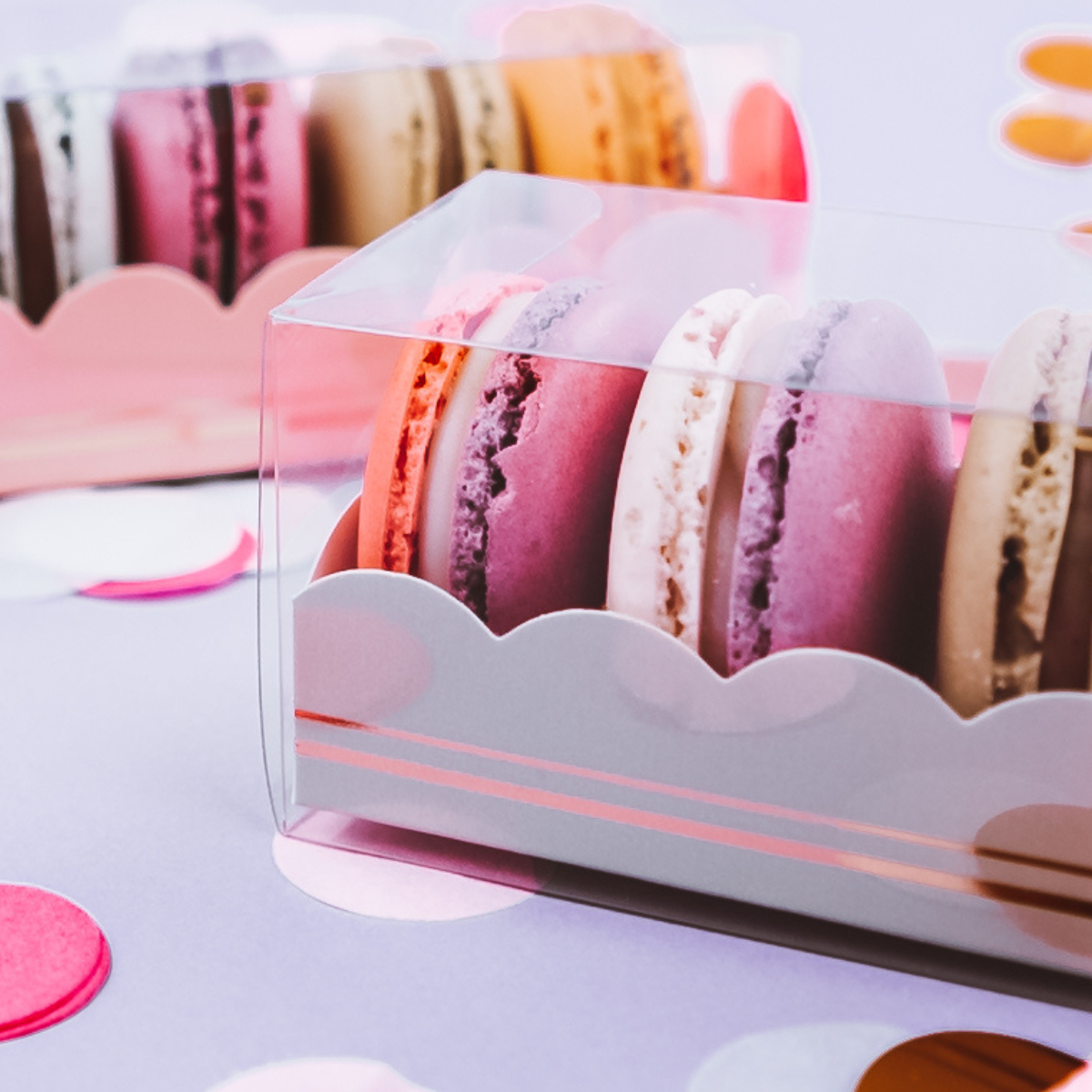 Dettaglio scatola trasparente piena di macarons sul viola 