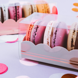 Dettaglio scatola trasparente piena di macarons sul viola 
