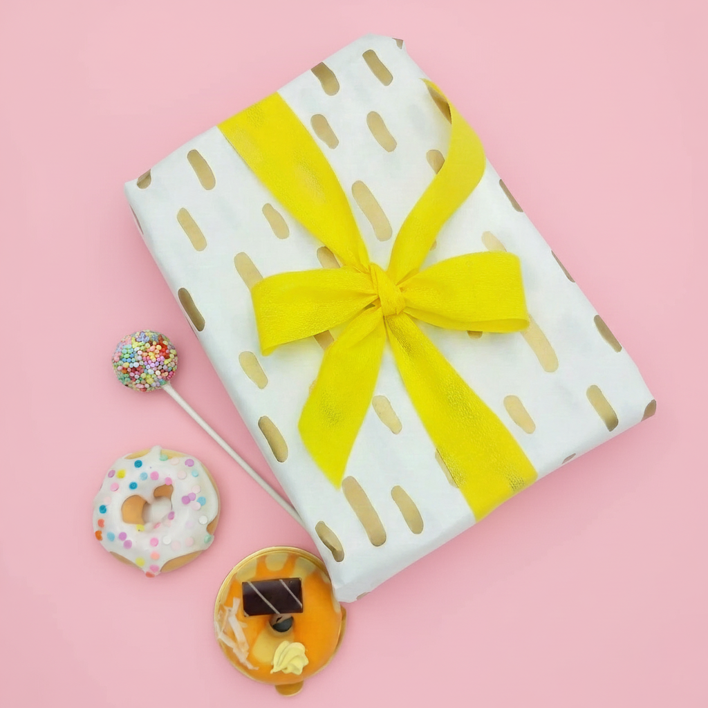 Carta pasticcera bianca con pois dorati che avvolge un pacco 