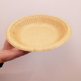 Piatto avana di carta monouso retto da una mano 