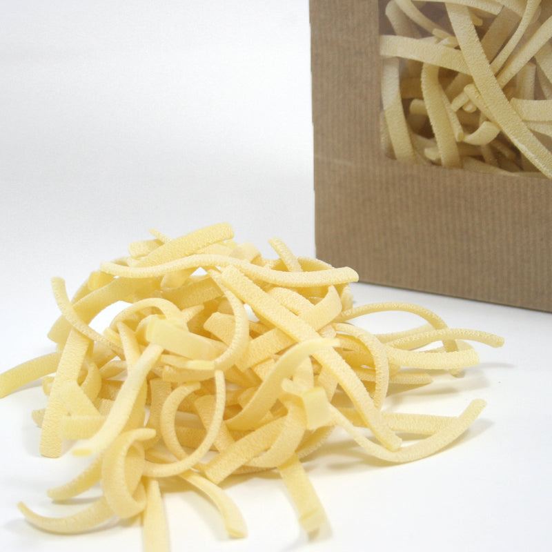 Sacchetto avana con finestra con pasta dentro, un po di pasta fuori. Dettaglio