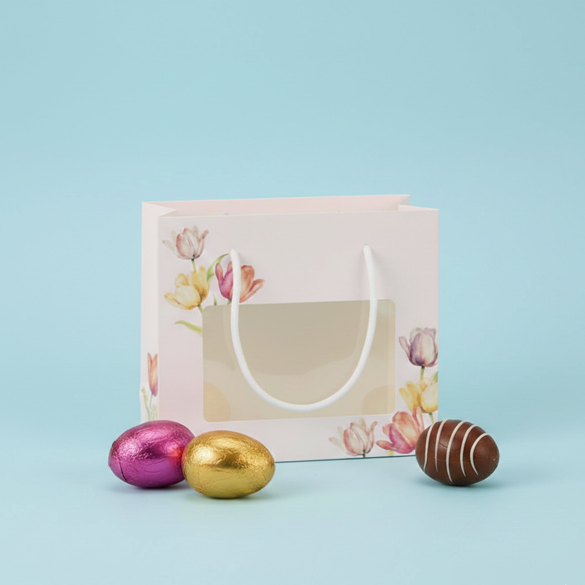 Shopper pasquale con finestra, aperta, vuota con vicino ovettini di chioccolata 