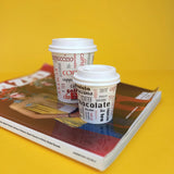 Bicchierini per caffe da asporto, con coperchio, due misure diverse, bianchi con grafica parole, su una rivista 