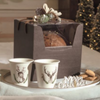 Scatola con finestra porta panettone, con panettone dentro, su vassoio con bicchieri ed elementi natalizi