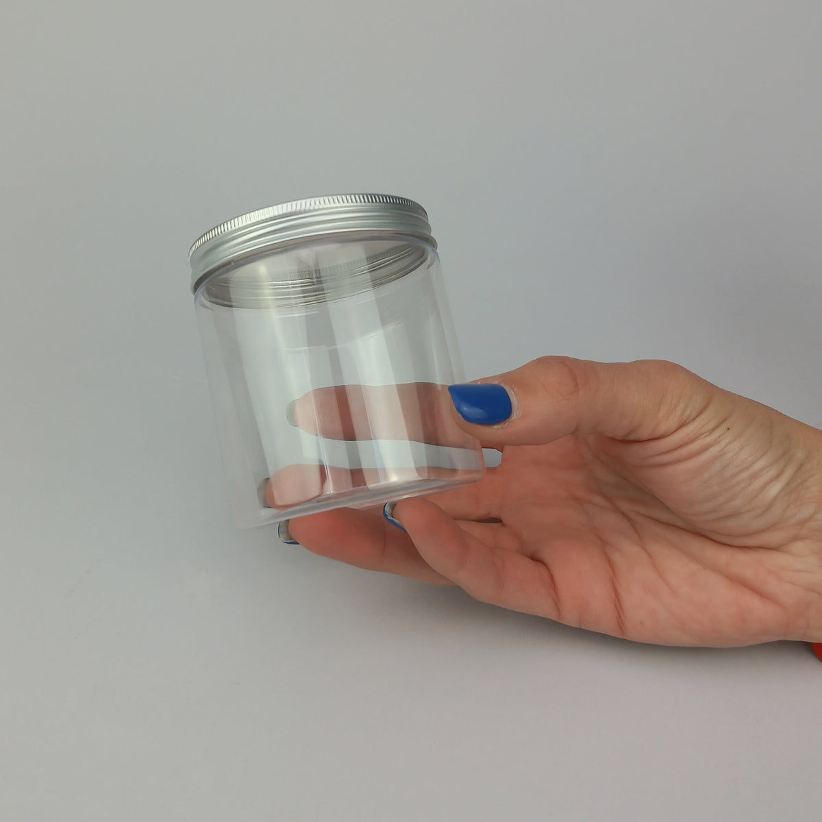 Barattolo trasparenti con tappo color argento tenuto in una mano 