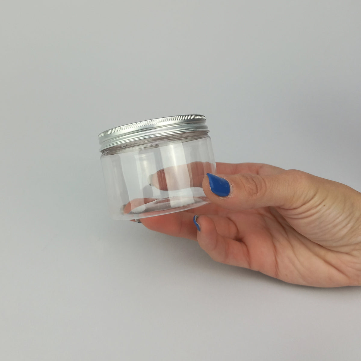 Barattolo trasparenti con tappo color argento tenuto in una mano 