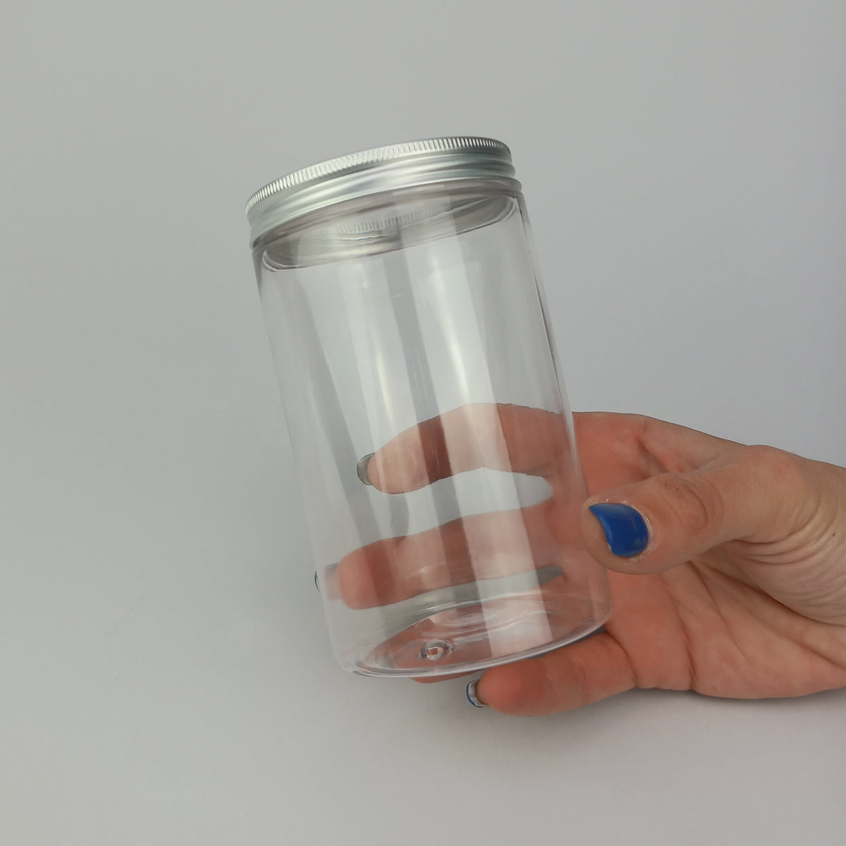 Barattolo trasparenti con tappo color argento tenuto in una mano 