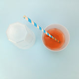 Bicchiere monouso visto dall'alto, uno rovesciato ed uno pieno di spritz con cannuccia bianca e blu 