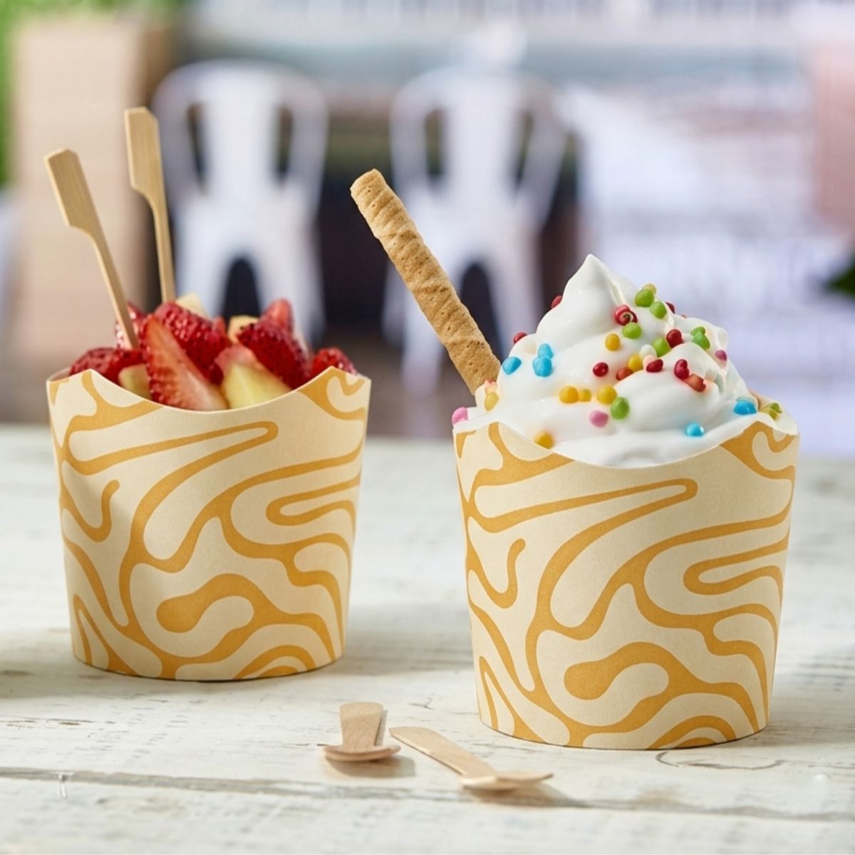 Bicchieri per gelato, mostrato nei suoi due lati , uno pieno di fragole ed uno di gelato bianco, su un tavolo di legno 