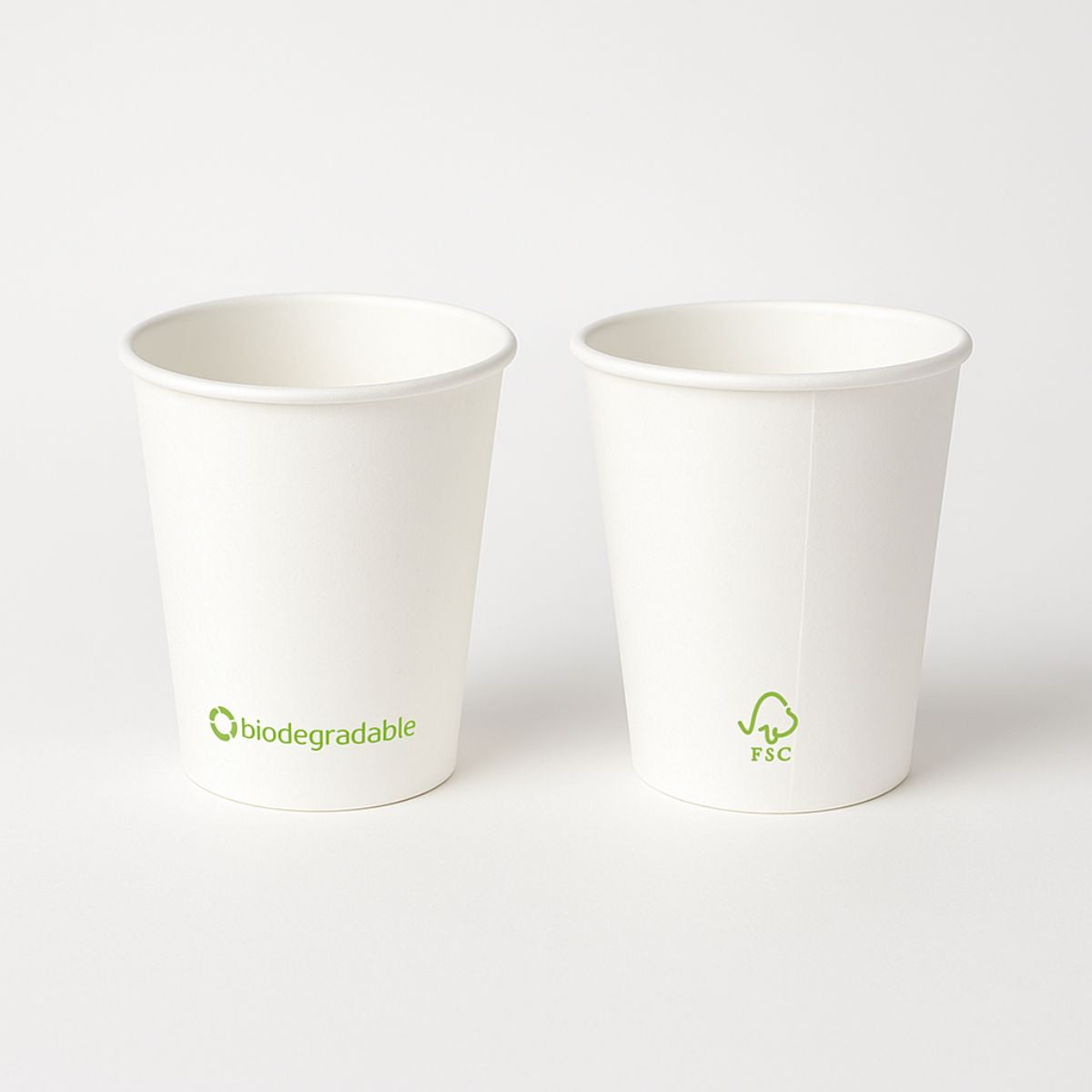 Bicchieri bianchi in carta, due. In entrambi sono riportati simboli biodegradabili