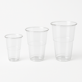 Bicchieri in plastica, trasparenti, monouso, in varie dimensioni, su sfondo bianco