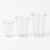 Bicchieri in plastica, trasparenti, monouso, in varie dimensioni, su sfondo bianco