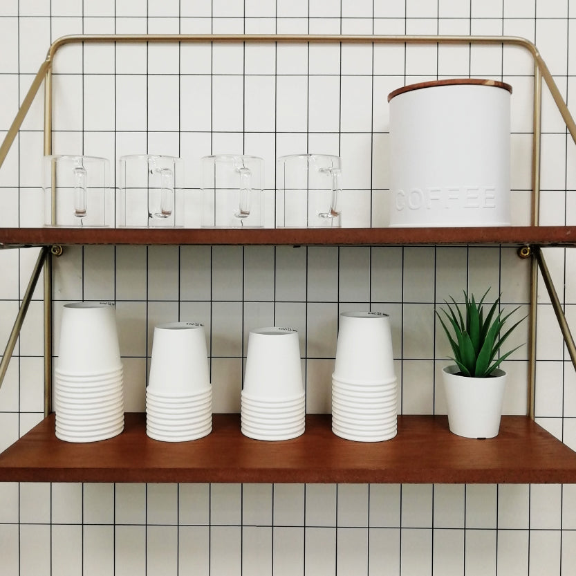 Mensola di una cucina con tazze trasparenti e bicchierini monouso bianchi per caffe 