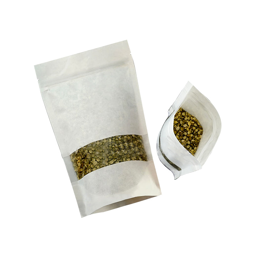 Busta bianca con zip e finestra, piena di semi, vista sdraiata da sopra aperta