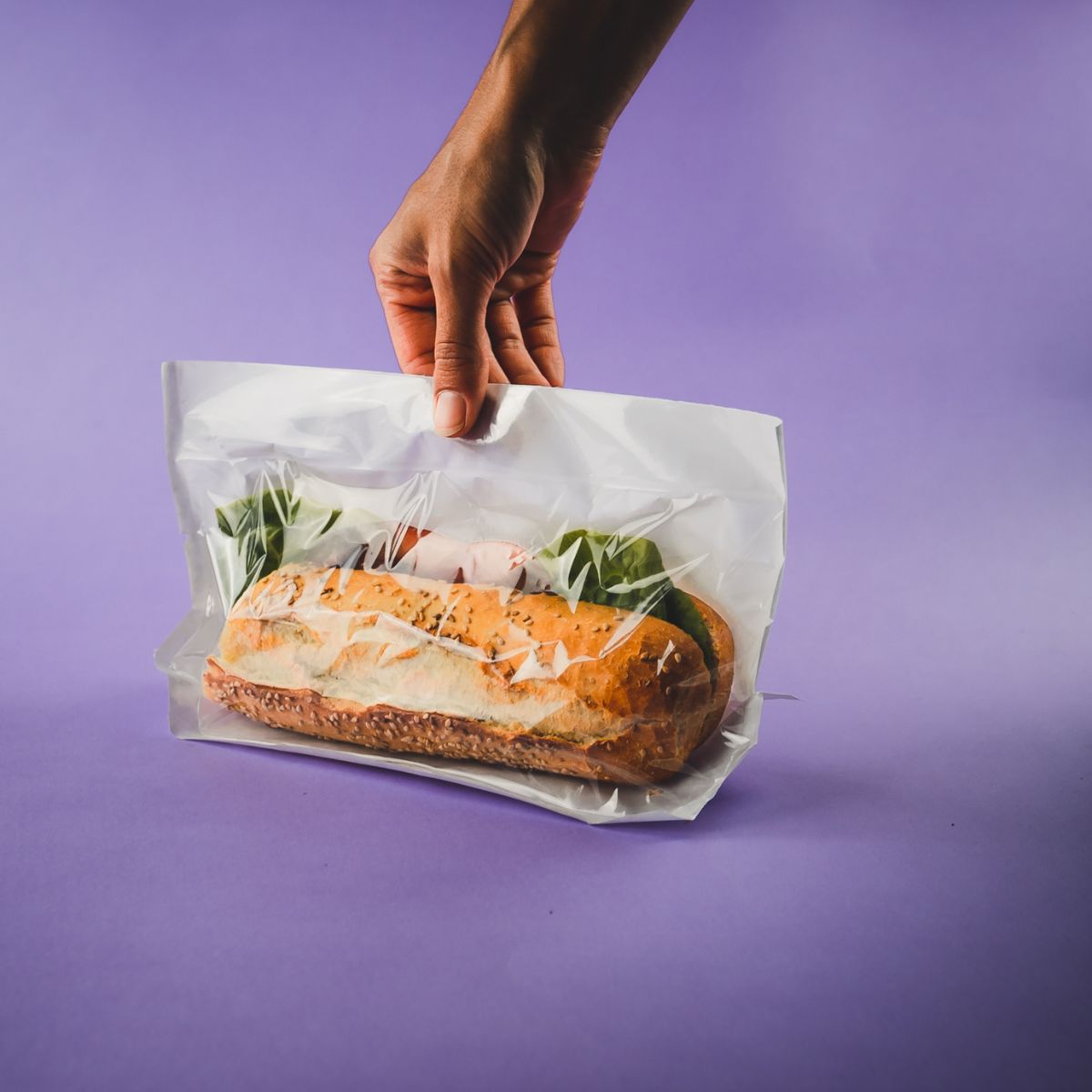 Mano che tiene un a busta sigillata con dentro panino 