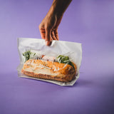 Mano che tiene un a busta sigillata con dentro panino 