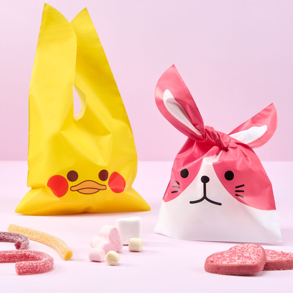 Busta per regalo pasquale a forma di papera e cane, caramelle vicino e sfondo rosa 